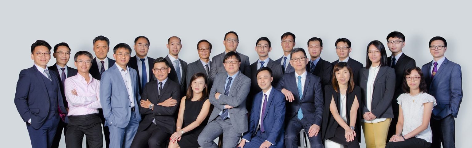 Group photo of professionals in business attire posing for a corporate team portrait.