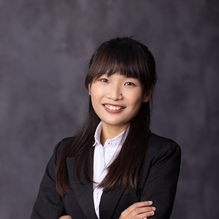 Professional portrait of a smiling woman in business attire with arms crossed.