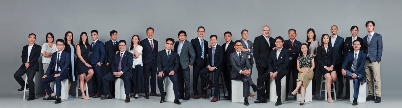 Group photo of professionals in business attire posing for a corporate team portrait.