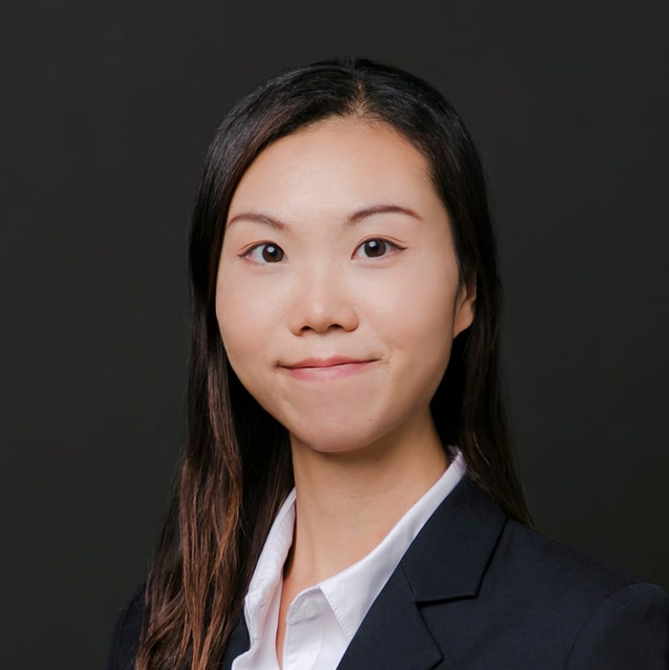 Professional headshot of a woman with dark hair wearing a suit and white shirt.