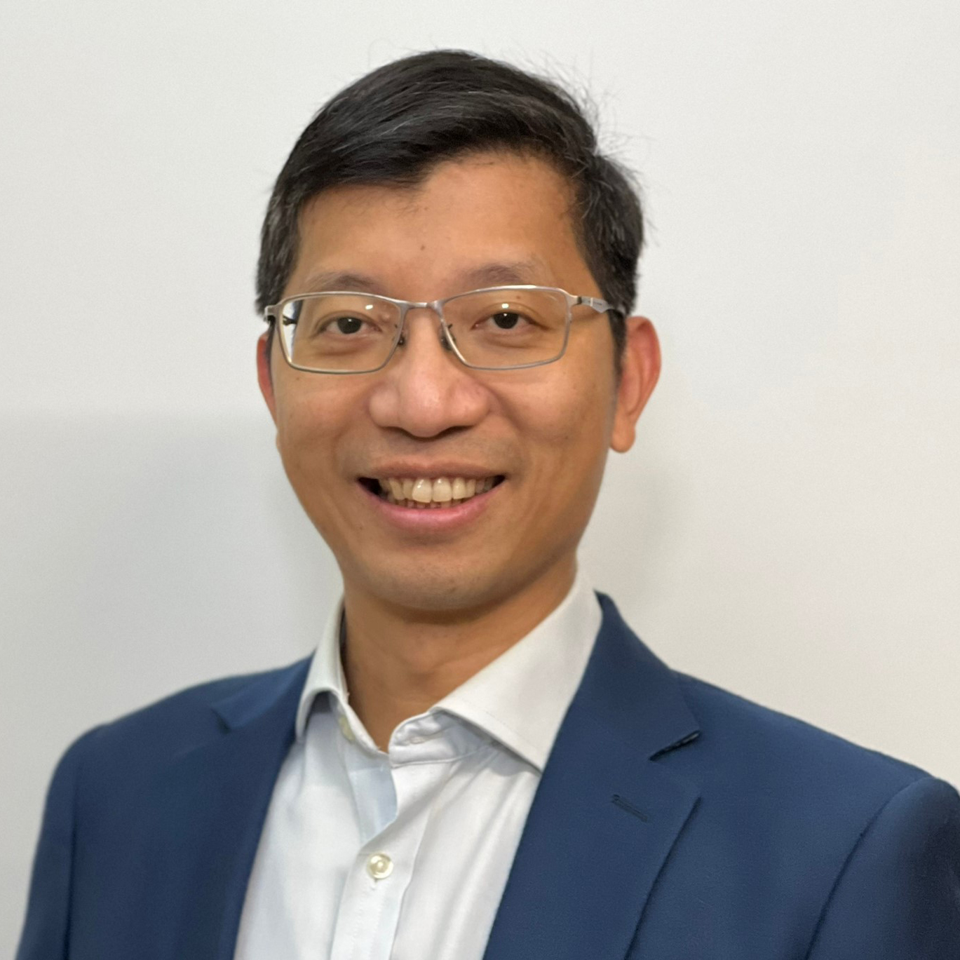 Smiling man with glasses wearing blue suit and white shirt