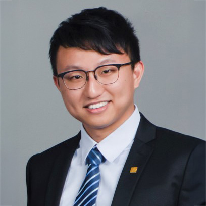 Professional headshot of a smiling man in suit and glasses