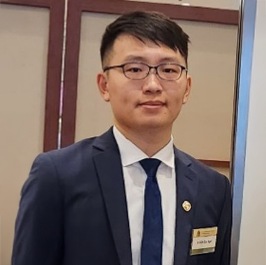 Man in suit and glasses wearing name badge