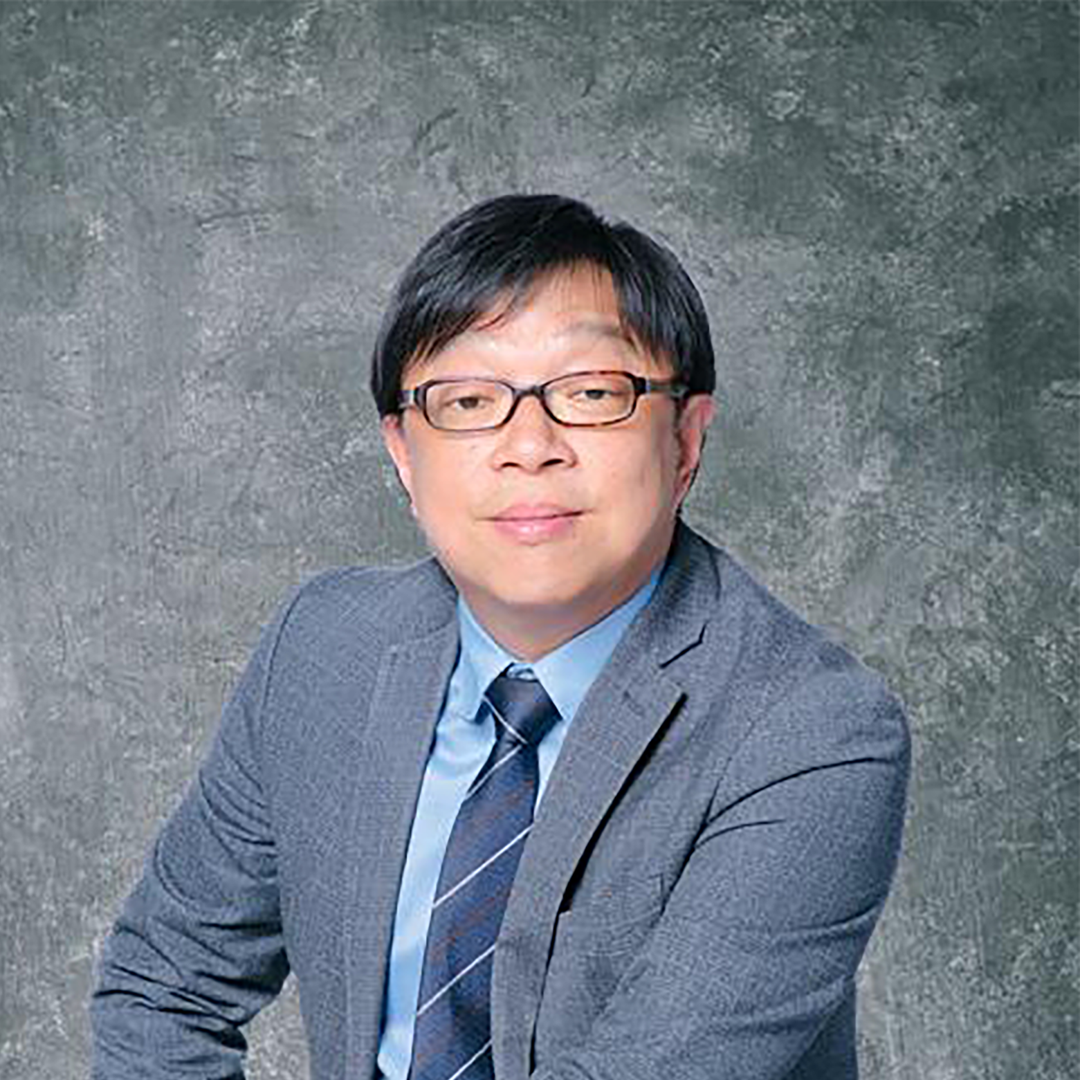 Man in glasses wearing gray suit and striped tie against textured gray background