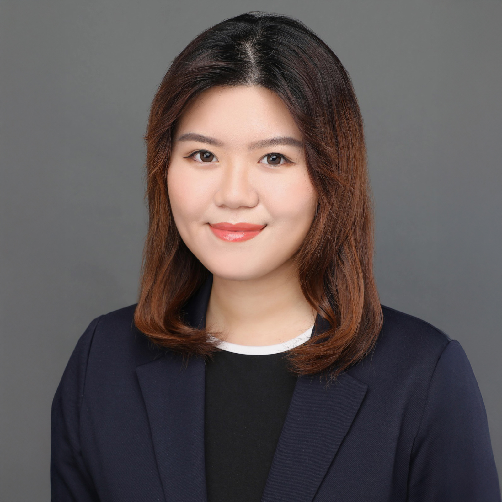 Professional headshot of a woman with shoulder-length brown hair wearing a dark blazer.