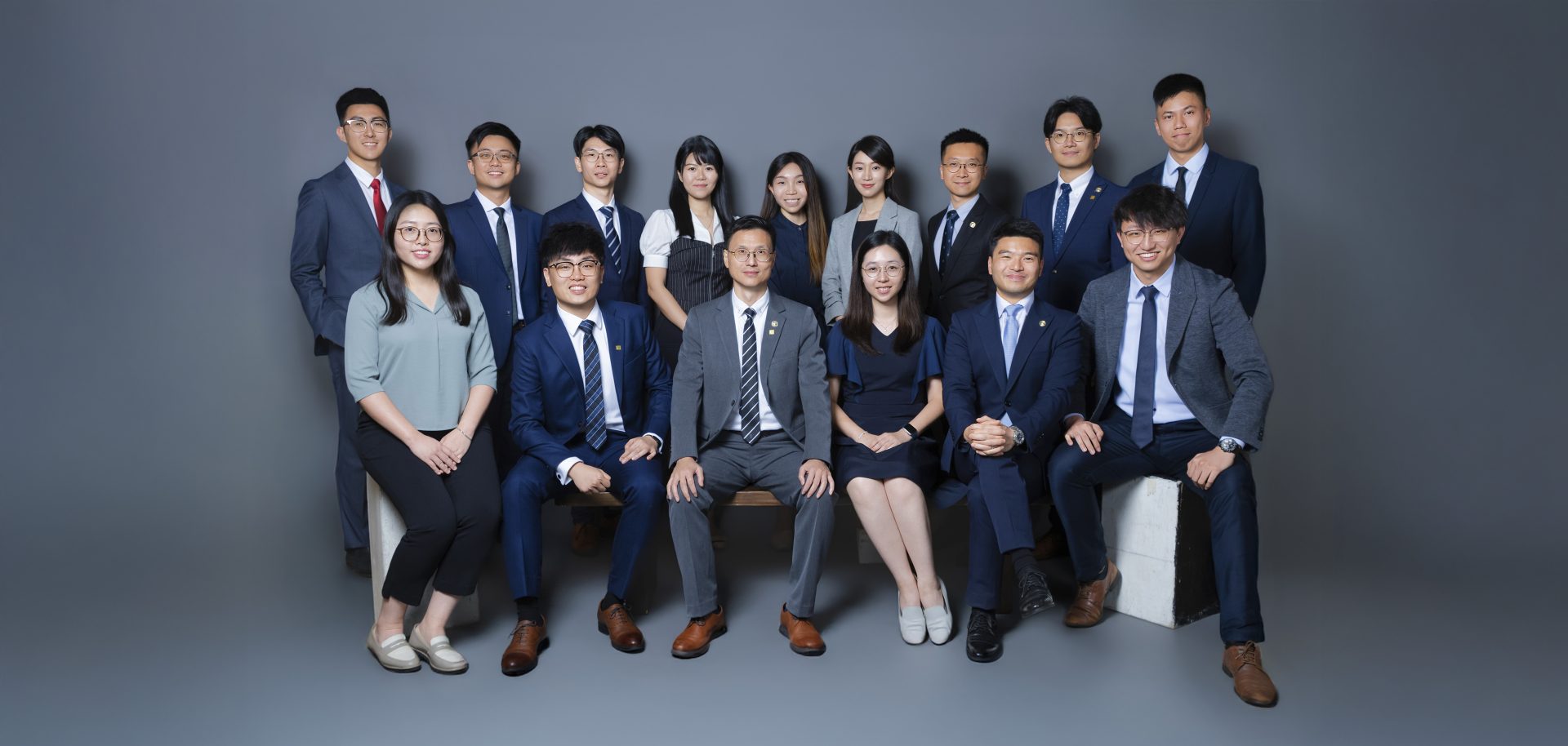 Group photo of professionals in business attire posing for a corporate team portrait.