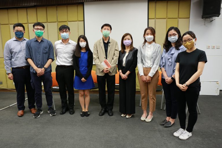 Group of eight people wearing face masks posing for a photo indoors