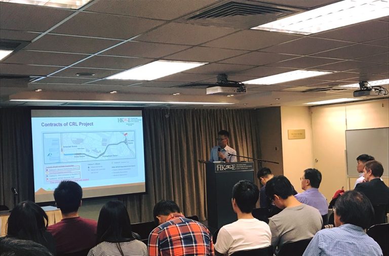 Person presenting CRL Project contracts to an audience in a conference room.