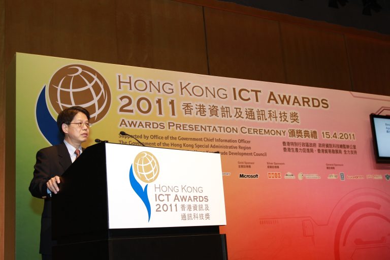 Man speaking at Hong Kong ICT Awards 2011 presentation ceremony podium.