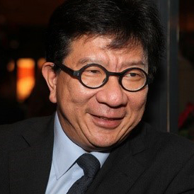 Man with round glasses and dark suit smiling