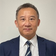 Portrait of a man in a blue suit and patterned tie.