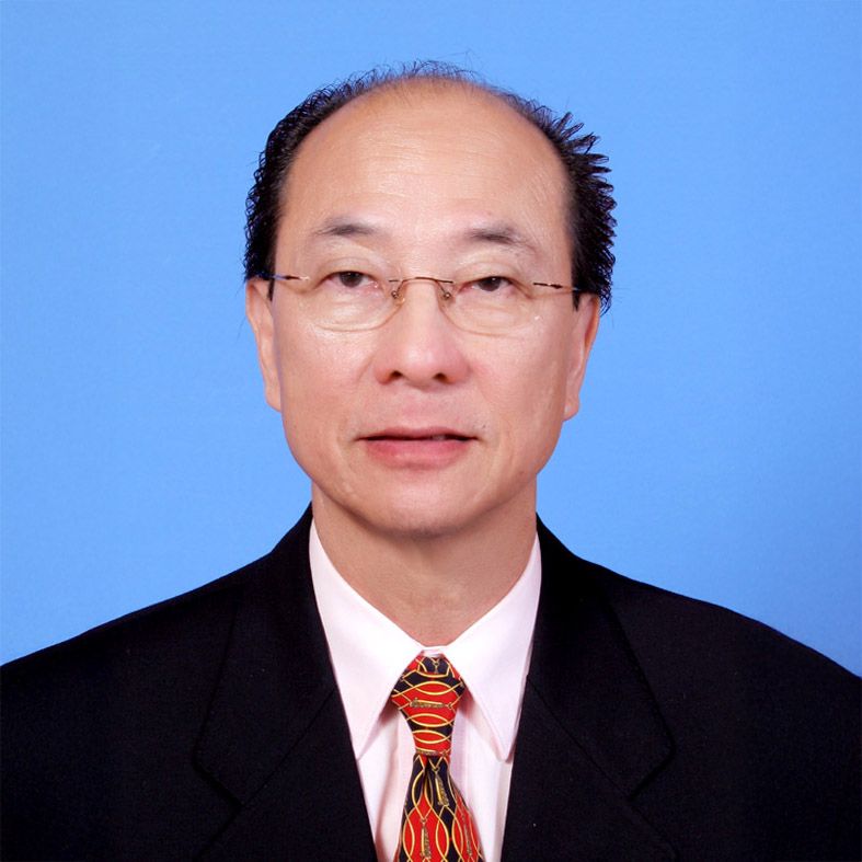 Portrait of Mervin Choy wearing glasses, suit, and patterned tie against blue background.