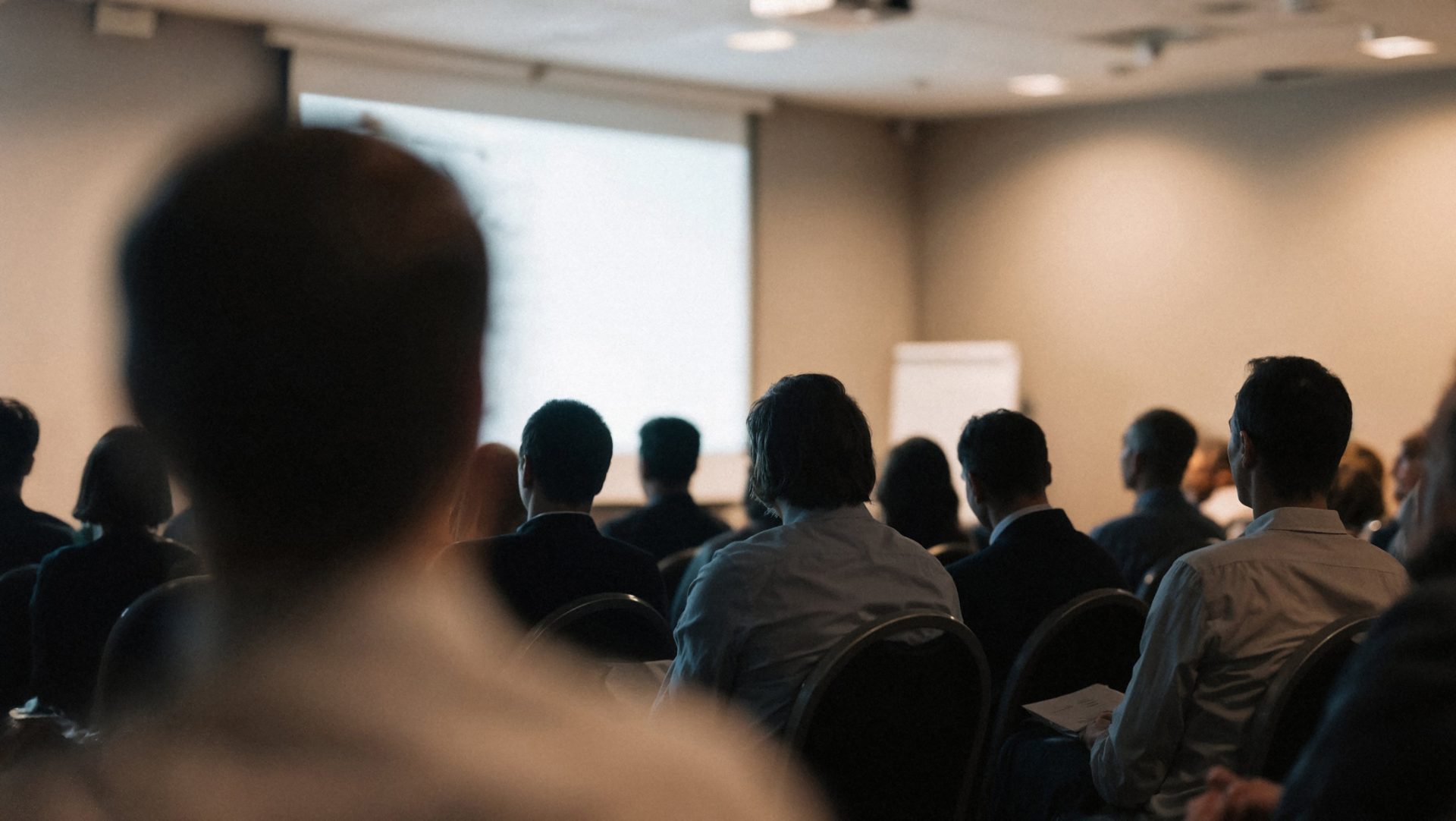 Audience seated in conference room facing presentation screen