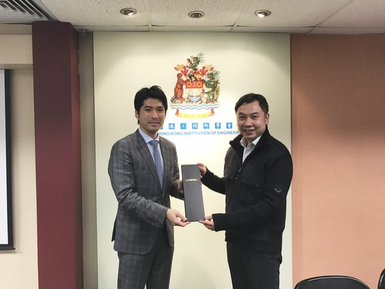 Two men exchanging a black award folder in front of Hong Kong Institution of Engineers logo.