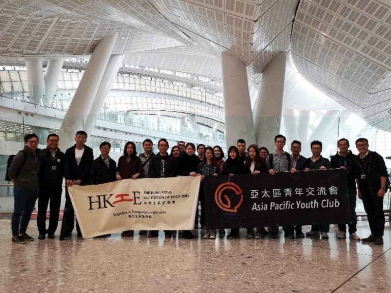 Group of people holding banners for HKIE Logistics & Transportation Division and Asia Pacific Youth Club in a modern building.