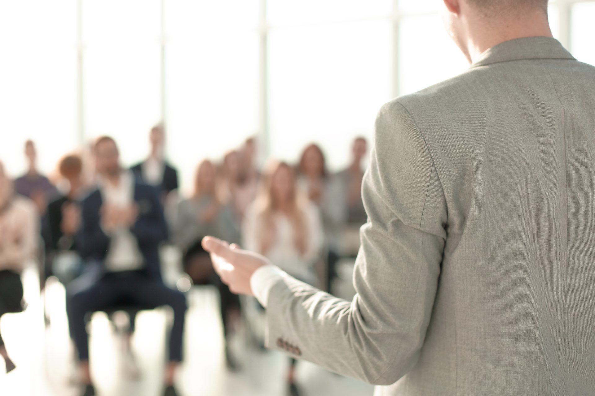Speaker presenting to audience in business seminar setting.