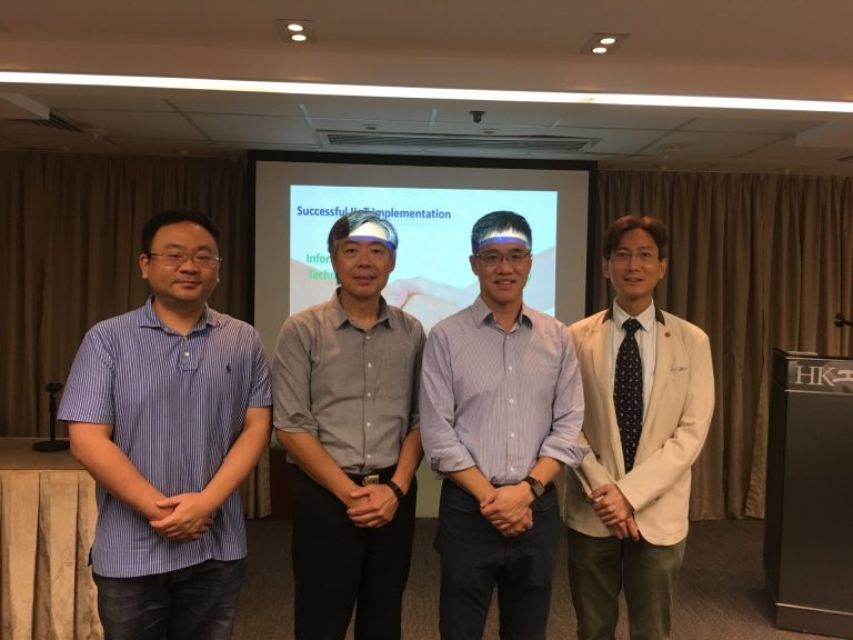 Four men posing in front of a presentation screen titled "Successful ICT Implementation"
