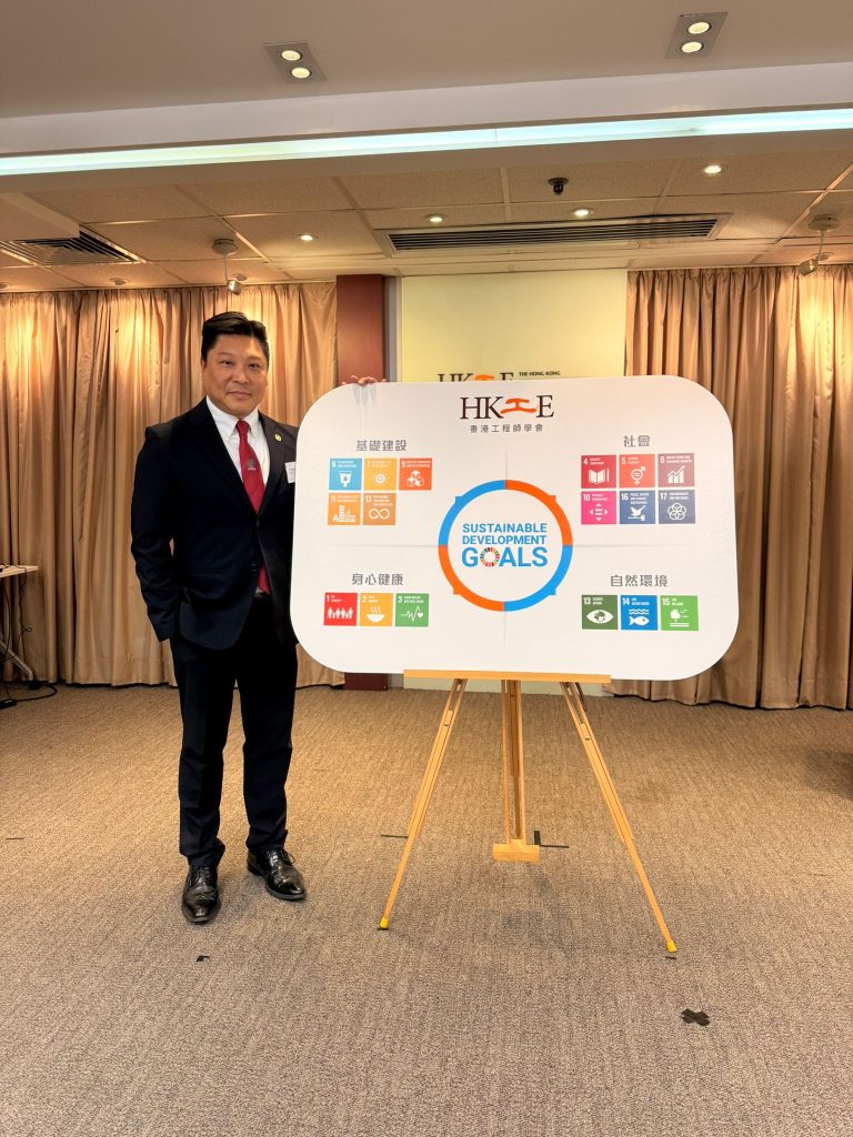 Man standing beside a display board showing Sustainable Development Goals icons.