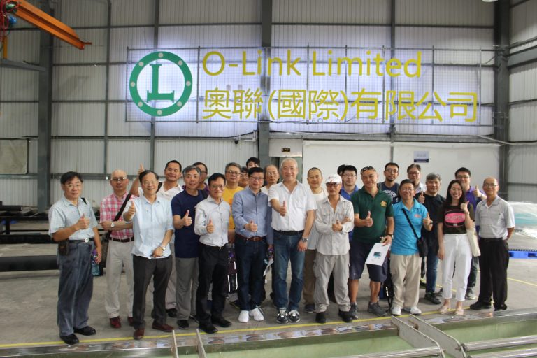 Group of people posing with thumbs up in front of O-Link Limited sign