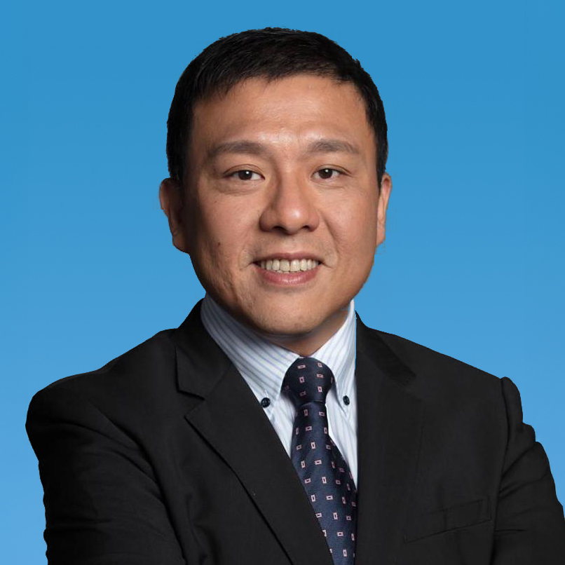 Professional headshot of a smiling man in suit and tie against blue background