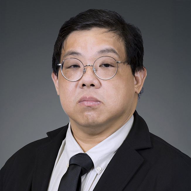 Man with round glasses wearing a suit and tie against a gray background