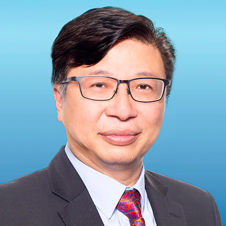Portrait of Eric Liu Sai Lok, wearing glasses and suit with patterned tie against blue background