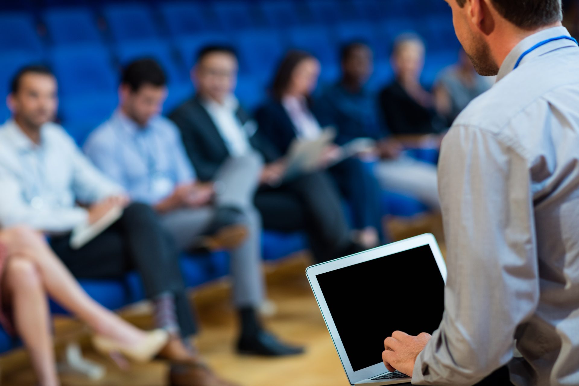 Business executives attending a meeting, one using a laptop.