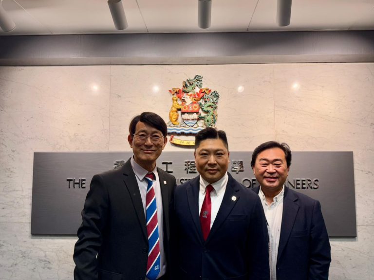 Three men in suits pose in front of The Hong Kong Institution of Engineers emblem.