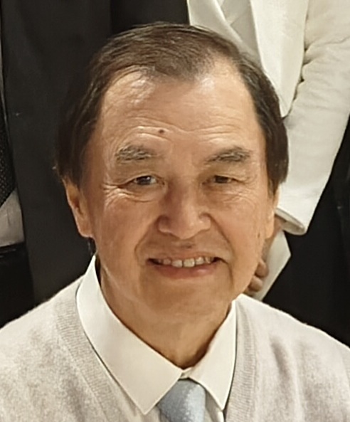Portrait of a smiling older man wearing a light sweater and tie.