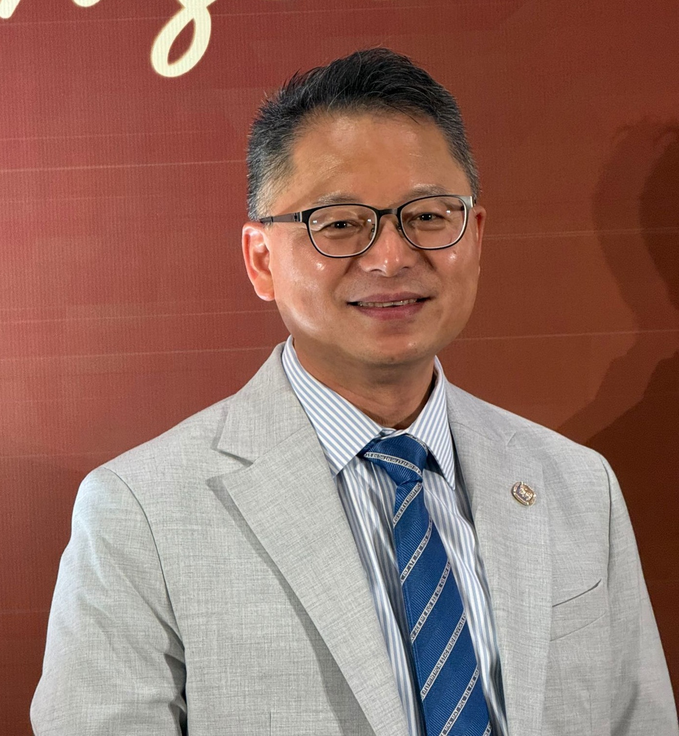 Man in glasses and suit smiling at camera