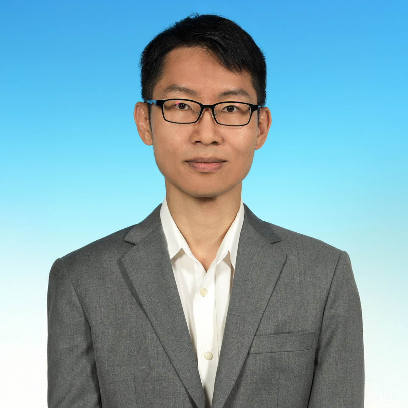Portrait of NG Pui Lam wearing glasses and a gray suit against a blue background.