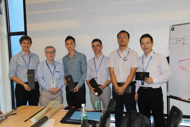 Six men in business attire standing in an office, holding awards or certificates.