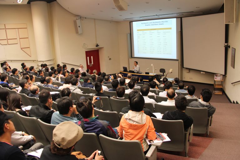 Audience attending lecture on stainless steel grades in auditorium.