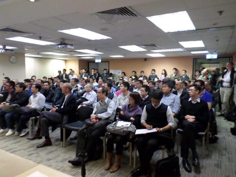 Audience seated in conference room listening attentively to presentation.