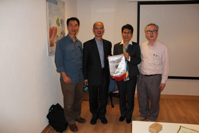 Four people posing indoors, one holding a banner for The Hong Kong Institution of Engineers.