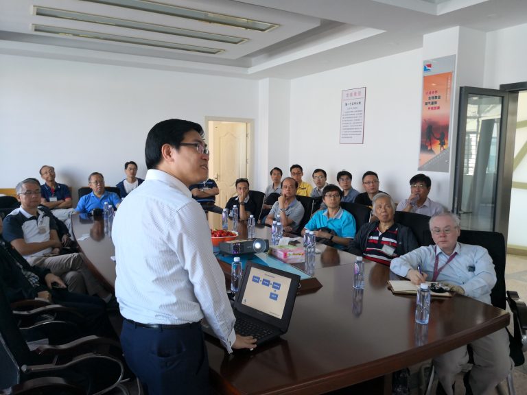 Man presenting to group in conference room with laptop displaying process flow.