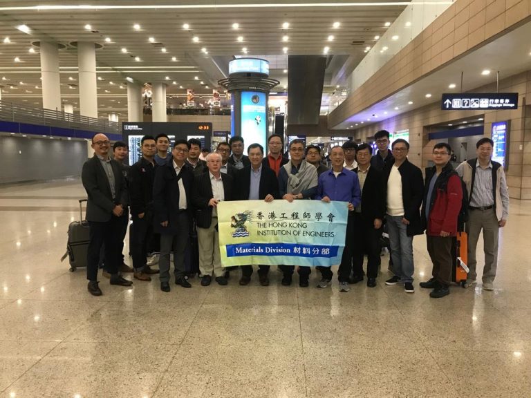 Group of engineers posing with banner at airport terminal