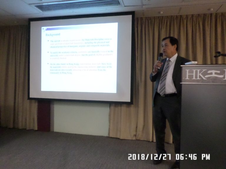 Man speaking at podium with microphone, presenting slide on materials discipline background.