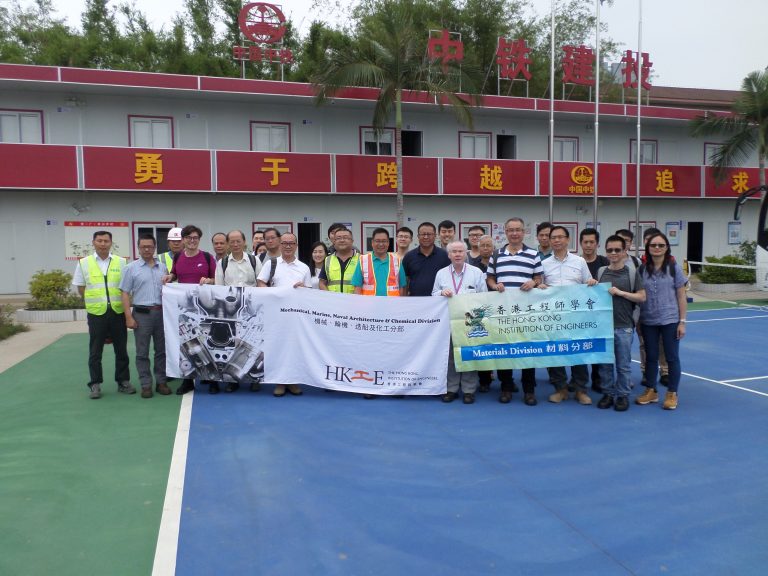 Group of engineers holding banners for HKIE divisions outside a building with Chinese characters.