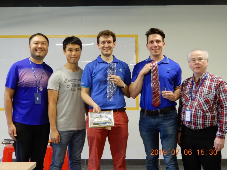 Five men posing together, two holding awards, one holding a framed picture, July 2019.