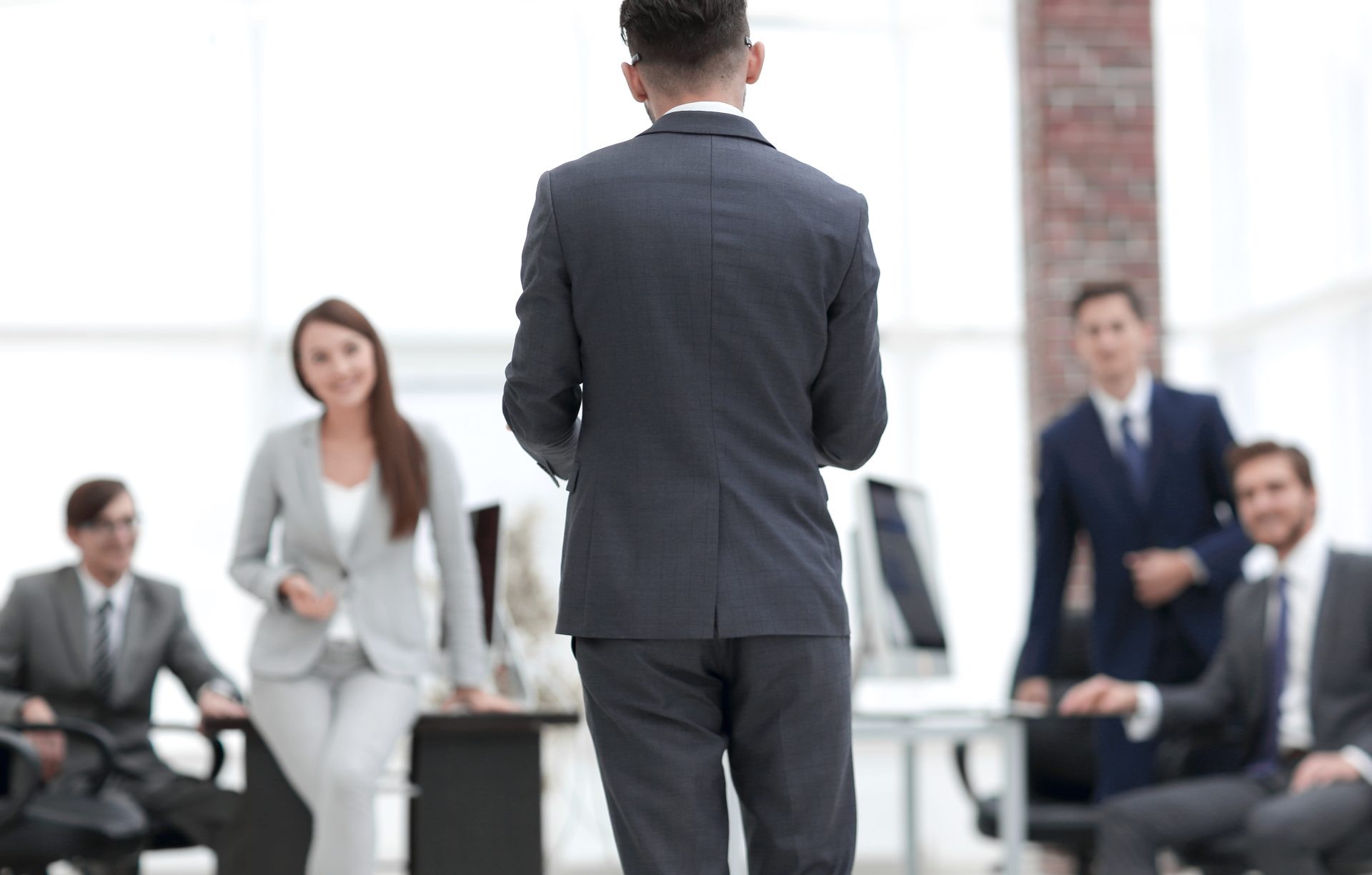 Subordinate approaches hospitable boss in office; colleagues observe warmly.