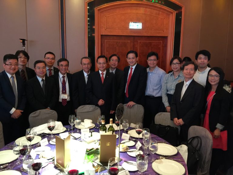 Group of professionals posing for photo at formal dinner event with table setting.