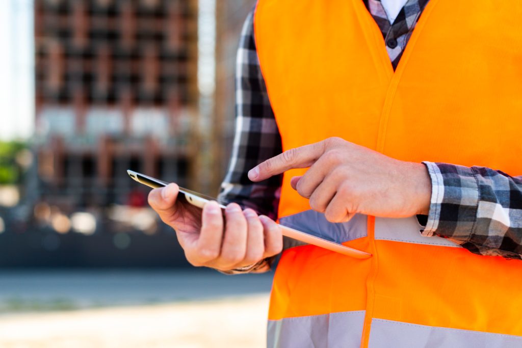 Person in safety vest using tablet on construction site