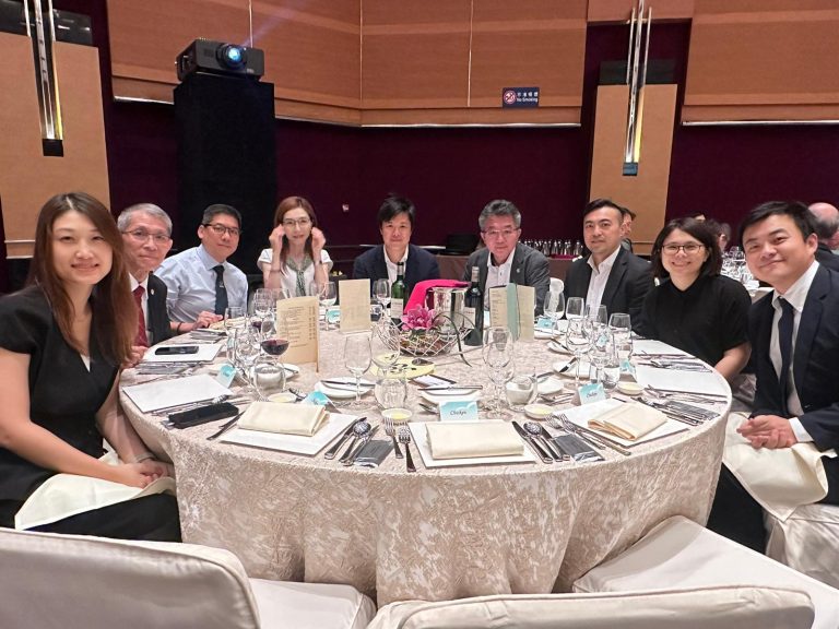 Group of people seated around a round dining table at a formal event.