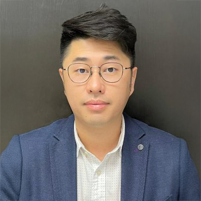 Portrait of a man with glasses wearing a blue blazer and white shirt.