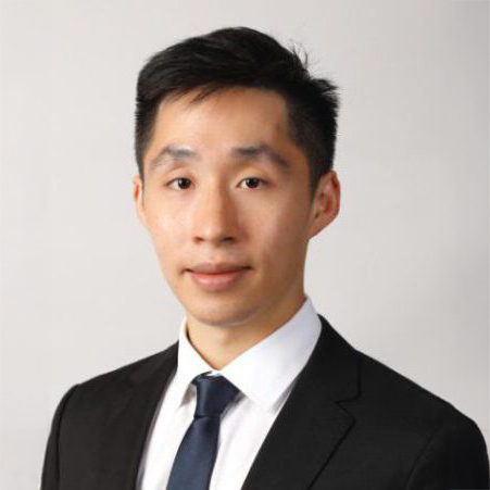 Portrait of a man in a suit and tie against a light background.
