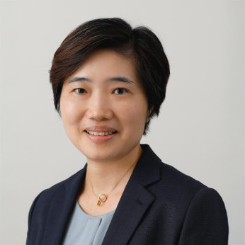 Professional headshot of a smiling woman with short dark hair wearing a blazer.