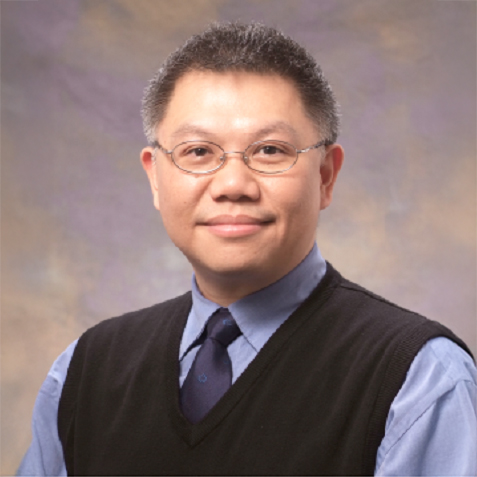 Portrait of Paul-Lam wearing glasses, a blue shirt, and a dark vest.