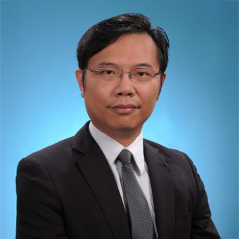 Professional headshot of a man in suit and glasses against blue background
