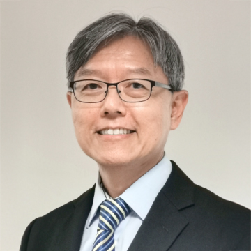 Portrait of a smiling man with glasses wearing a suit and striped tie.